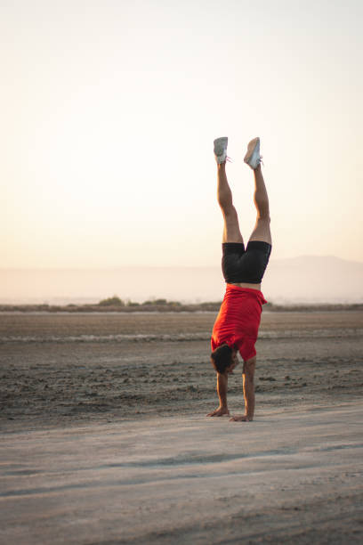 jeune homme sportif exerçant à l’extérieur faisant l’entraînement de gymnastique et le headstand - inversion yoga photos et images de collection