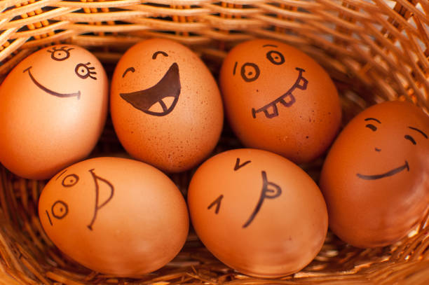 istock Stack of hand drawn smiley eggs on straw basket with colorful candy, easter preparation, holiday mood concepts 1309559225