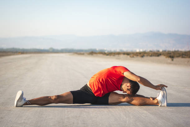 giovane atleta maschio che si allunga prima di allenarsi nella natura in estate - sunset yoga young men caucasian foto e immagini stock