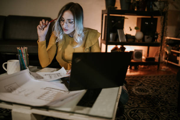 istock Young woman working on a late night project in her home 1309559971