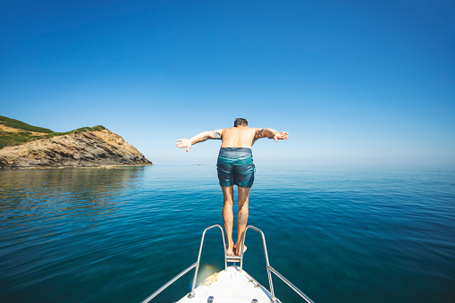 Young adult man diving from his yacht