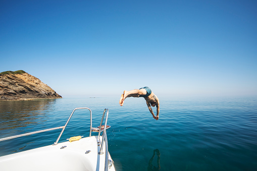 Young adult man diving from his yacht