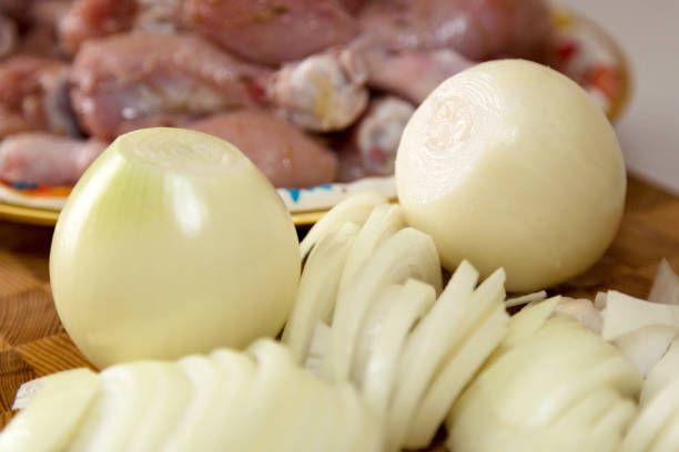 istock Sliced onion and raw chicken meat on wood background 1309560873