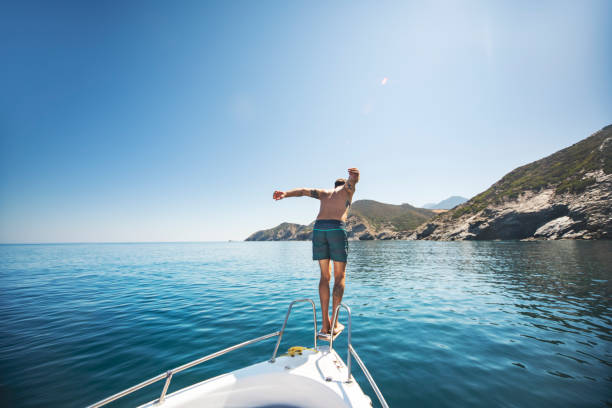 młody dorosły człowiek nurkujący ze swojego jachtu - clear sky water sports and fitness yacht zdjęcia i obrazy z banku zdjęć