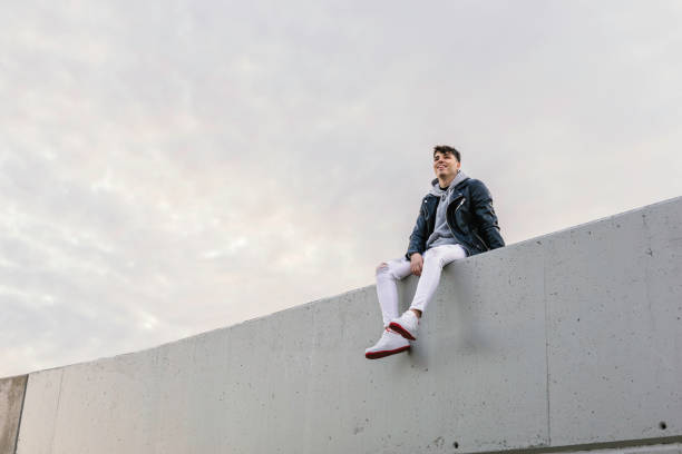 istock Happy young boy sitting on a wall 1309561858