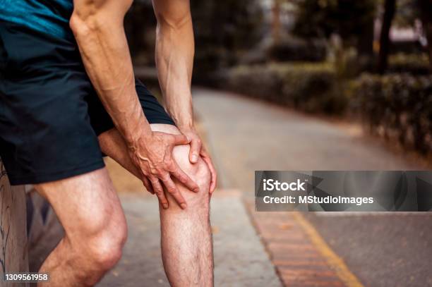 The Athlete Holds On To His Knee As He Feels Pain Stock Photo - Download Image Now - Pain, Muscular Build, Physical Injury