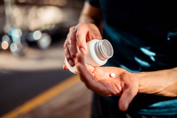 Close up of human hands. He is taking pill Close up of human hands. Man holding the medicine bottle in one hand and pill in other nutritional supplement stock pictures, royalty-free photos & images