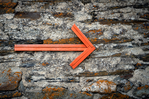 Orange color wood arrow hanging on the wall signpost for your needs.