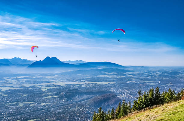 zwei gleitschirme über salzburg in österreich, paragliding vom gaisberg - paragliding sport austria parachuting stock-fotos und bilder