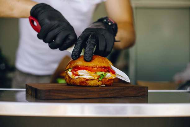 istock chef in black gloves cuts a burger with his knife 1309564263