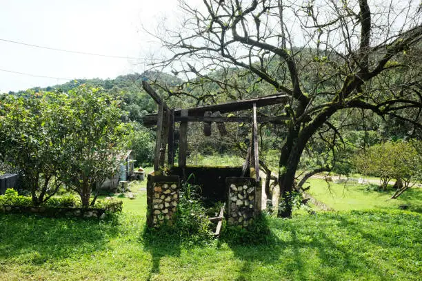 Outdoor old Stone Artesian water-Well with vintage bucket in the garden at countryside of Thailand