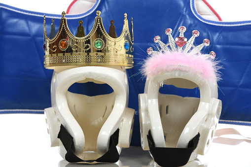 Martial arts protective helmets with crowns in front of a protective sparring chest pad.