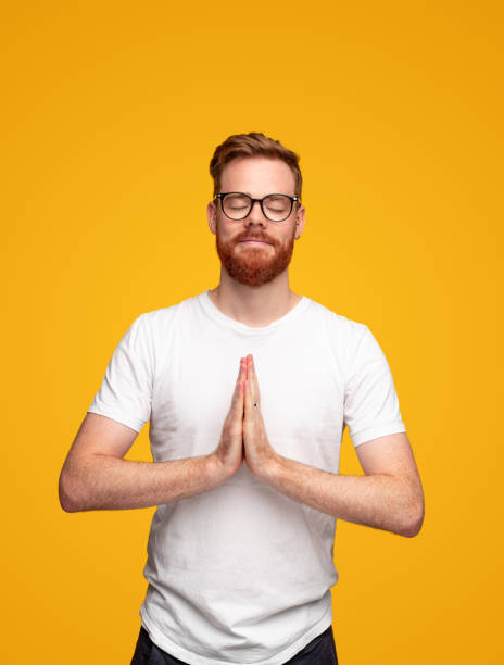 uomo zenzero che medita con le mani di preghiera - vertical caucasian glasses red hair foto e immagini stock