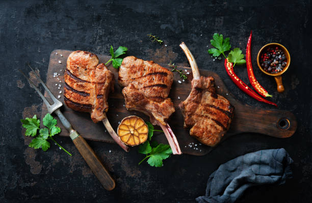 chuletas de costillas de carne de ternal a la plancha con ingredientes sobre fondo rústico oscuro - veal rack fotografías e imágenes de stock