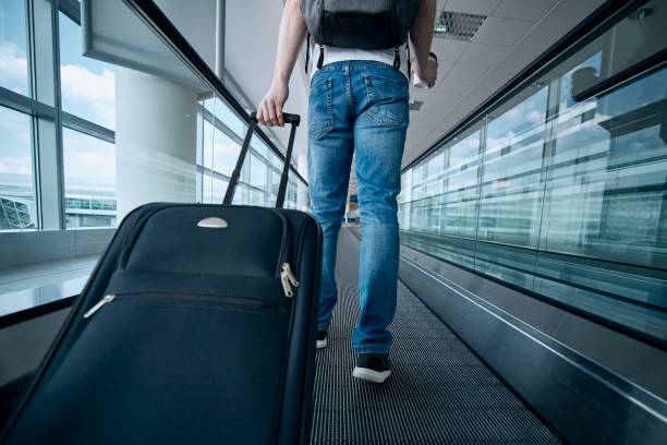 uomo che cammina con la valigia al terminal dell'aeroporto - moving walkway escalator airport walking foto e immagini stock