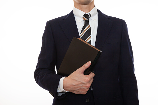 A man in a suit holding a book, front