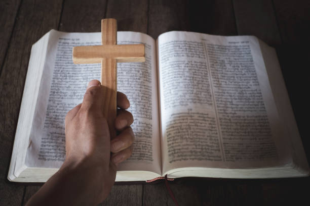 The crucifix in human hands rests on the Bible. Concepts for the study of Christians, Christianity, Catholicism, God, Heaven, Heaven, God or God. God helps to repent, pray for Easter, Catholic Lent. el crucifijo en manos humanas descansa sobre la biblia. conceptos para el estudio de los cristianos, el cristianismo, el catolicismo, dios, el cielo, el cielo, dios o dios. dios ayuda a arrepentirse, orar por la pascua, la cuaresma católica.