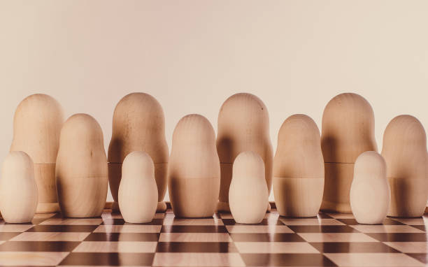 istock Two rows of impersonal nesting dolls on a chessboard. Conceptual image. 1309574545