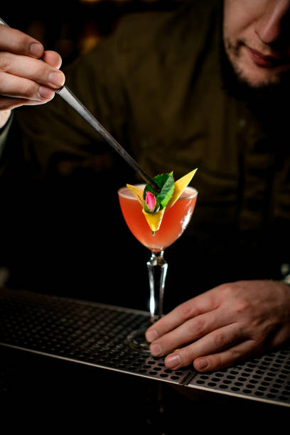 istock male bartender expertly decorates cocktail glass by small green leaf using tweezers 1309574584