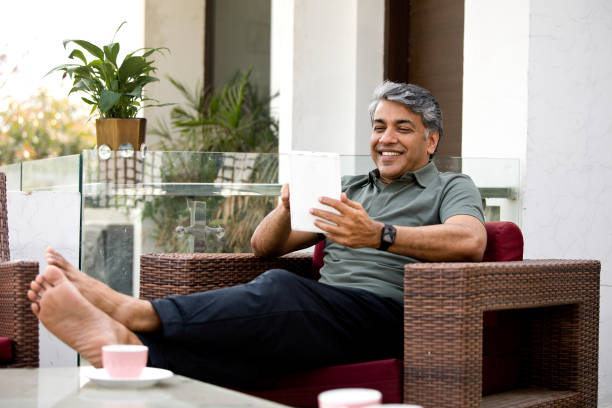 istock Happy man watching media content on digital tablet on armchair 1309576113