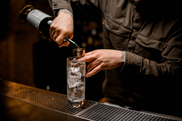 istock glass with ice cubes stands on bar and bartender pours drink from bottle into jigger 1309578988