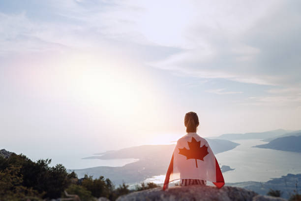 девушка-подросток, сидящая на вершине горы с канадским флагом на плечах - toronto canada flag montreal стоковые фото и изображения