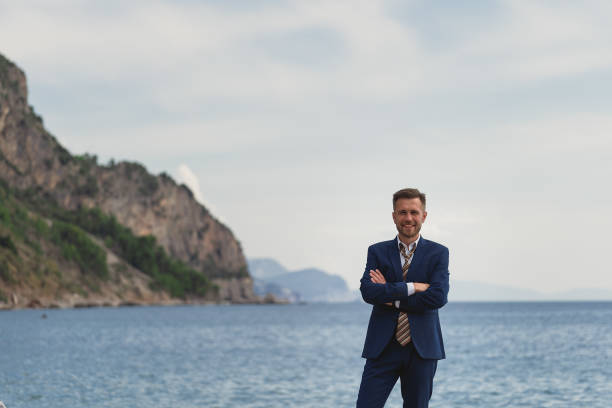 istock Businessman standing on the beach in a suit 1309581084