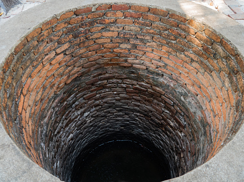 Old well made of red bricks located in village. Close up image.