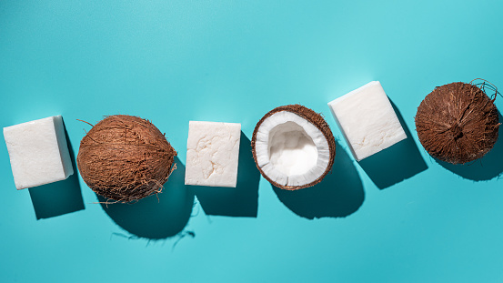 Body hygiene fatlay with coconut handmade soap and coco on blue background, hard shadow, top view