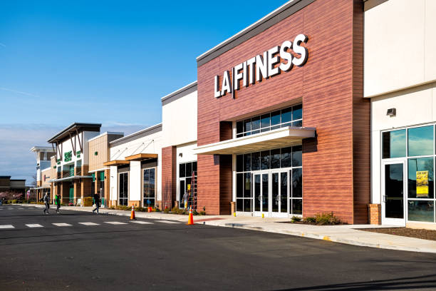 LA Fitness membership gym store with outdoors outside facade view at shopping strip mall in Northern Virginia with people walking Herndon, USA - March 18, 2020: LA Fitness membership gym store with outdoors outside facade view at shopping strip mall in Northern Virginia with people walking herndon virginia stock pictures, royalty-free photos & images