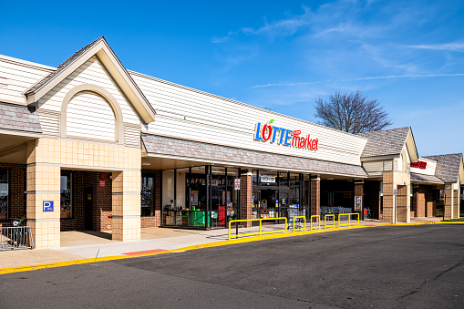 Herndon, USA - March 18, 2020: Exterior street in strip shopping mall with Lotte Asian Korean market store shop entrance selling grocery produce in Virginia Fairfax County