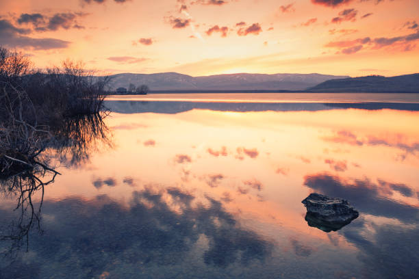 Beautiful sunset on the shore of lake in early spring. Beautiful sunset on the shore of lake in early spring. Sky with clouds reflected in the calm water surface. Bashkortostan, Russia south ural stock pictures, royalty-free photos & images