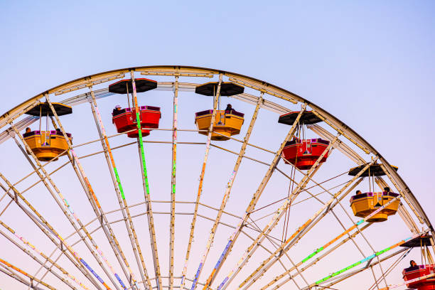 plan rapproché de la grande roue avec des gondoles au stationnement pacifique d’isolement contre le ciel coloré au coucher du soleil - ferris wheel santa monica pier santa monica wheel photos et images de collection