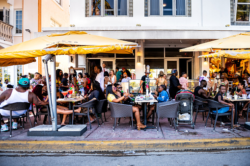 Miami Beach, USA - May 5, 2018: People sitting eating drinking at Voodoo lounge bar restaurant in South Beach, Florida on Ocean drive by Art Deco district Walk Hostel