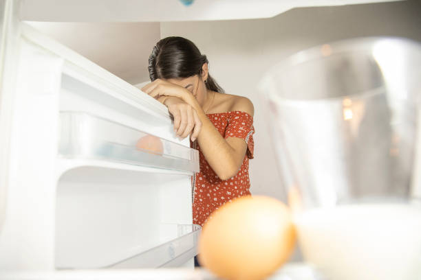 woman worried about food shortage, post pandemic concept woman leaning on the fridge door without food fridge issues stock pictures, royalty-free photos & images