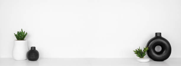 istock Modern black and white home decor and plants on a white shelf against a white wall banner 1309593316