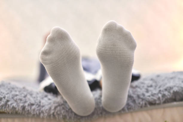 Woman resting on sofa in cozy soft comfortable socks. Female feet in white cotton socks, close up.