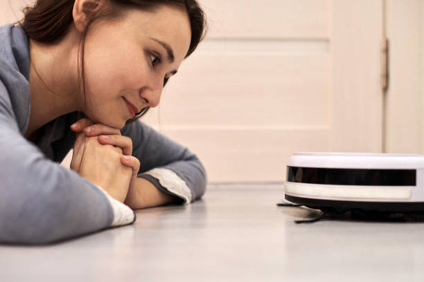 istock Friendly cheerful woman looking at robotic vacuum cleaner. 1309593664