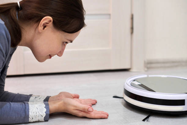 istock Friendly cheerful woman looking at robotic vacuum cleaner. 1309593778