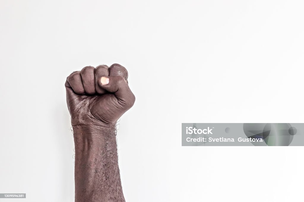 Male hand clenched into a fist on a white background. A symbol of the struggle for the rights of blacks in America. Protest against racism. Male hand clenched into a fist on a white background. A symbol of the struggle for the rights of blacks in America. Protest against racism George Floyd Protests Stock Photo