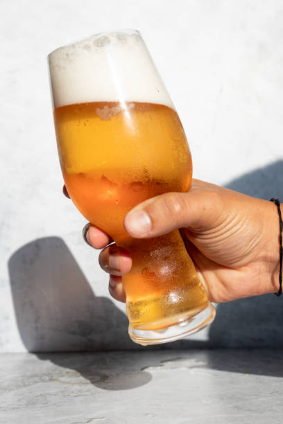 istock Hand holding a glass with foamy IPA beer 1309596577