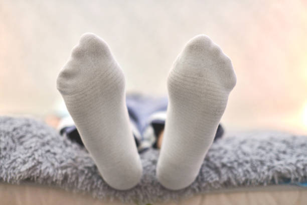 istock Woman resting on sofa in white striped socks, close up. 1309597496