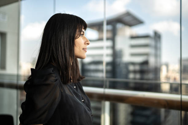 istock Young woman looking at view from apartment's balcony 1309600099