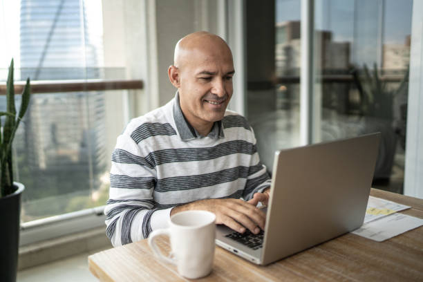 istock Mid adult man using laptop working at home 1309600580