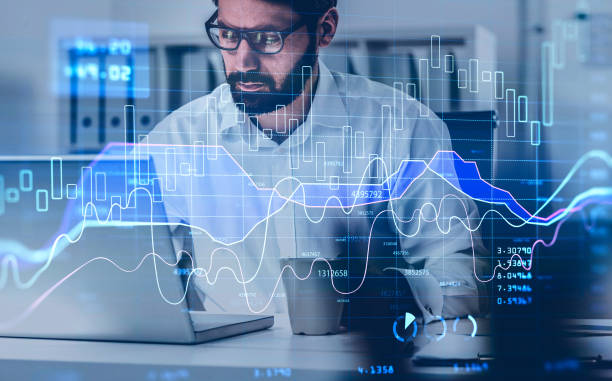 istock Handsome beard trader in glasses analyzing stock graph chart under the bases of fundamental analysis, front view businessman working on laptop. Double exposure. Internet trading 1309600809