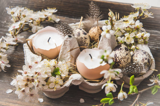 istock Candles in eggshells, quail eggs and white blossoming apple tree branches on a wooden tray as an Easter decoration 1309601599