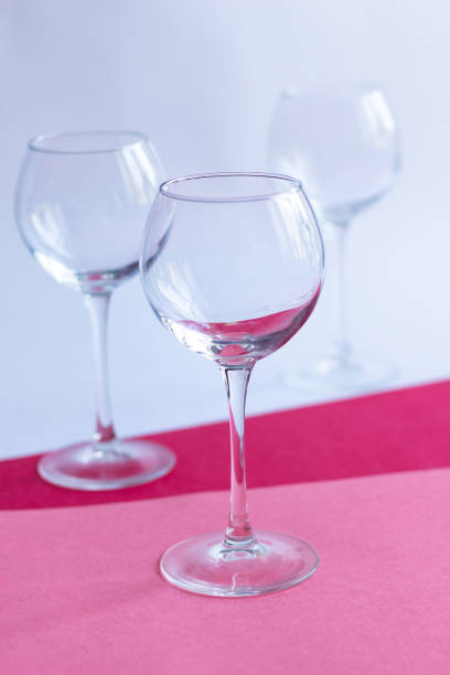 istock Empty wine glasses on white, rose, red paper background 1309602036