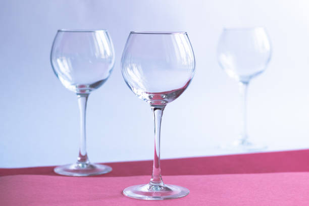 istock Empty wine glasses on white, rose, red paper background 1309602042