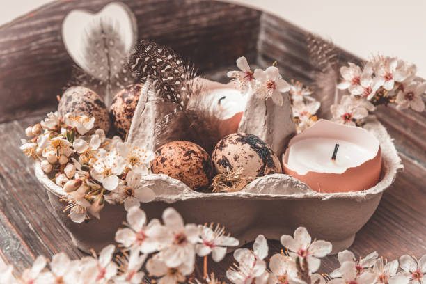 istock Candles in eggshells, quail eggs and white blossoming apple tree branches on a wooden tray as natural Easter decoration 1309602058