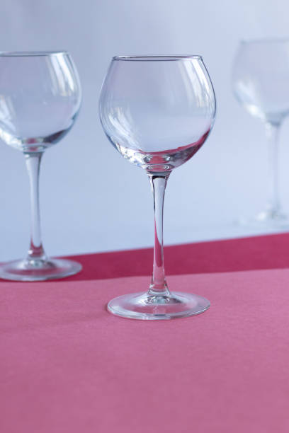 istock Empty wine glasses on white, rose, red paper background 1309602066